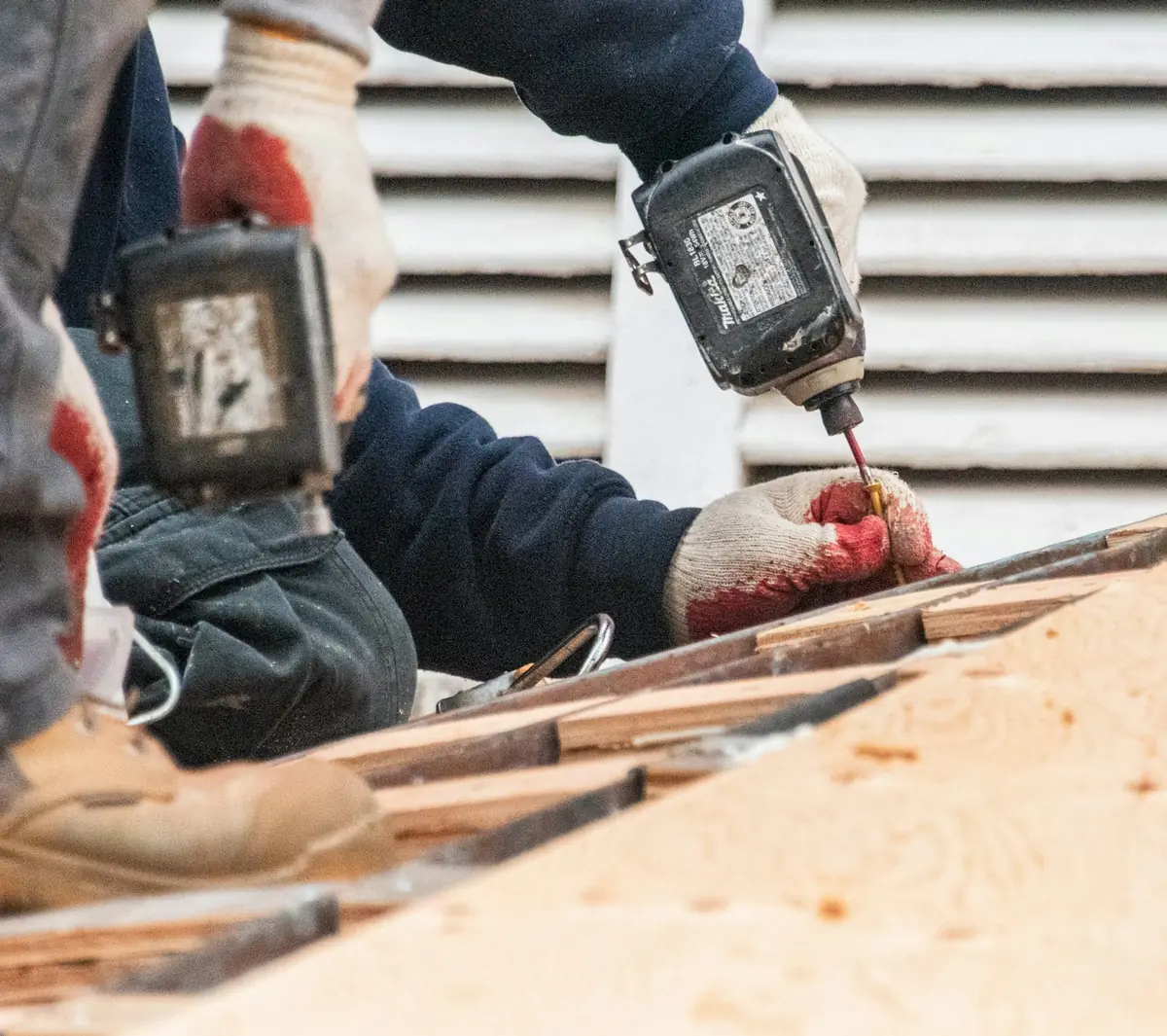 Close-up of a worker using a power drill on roof decking